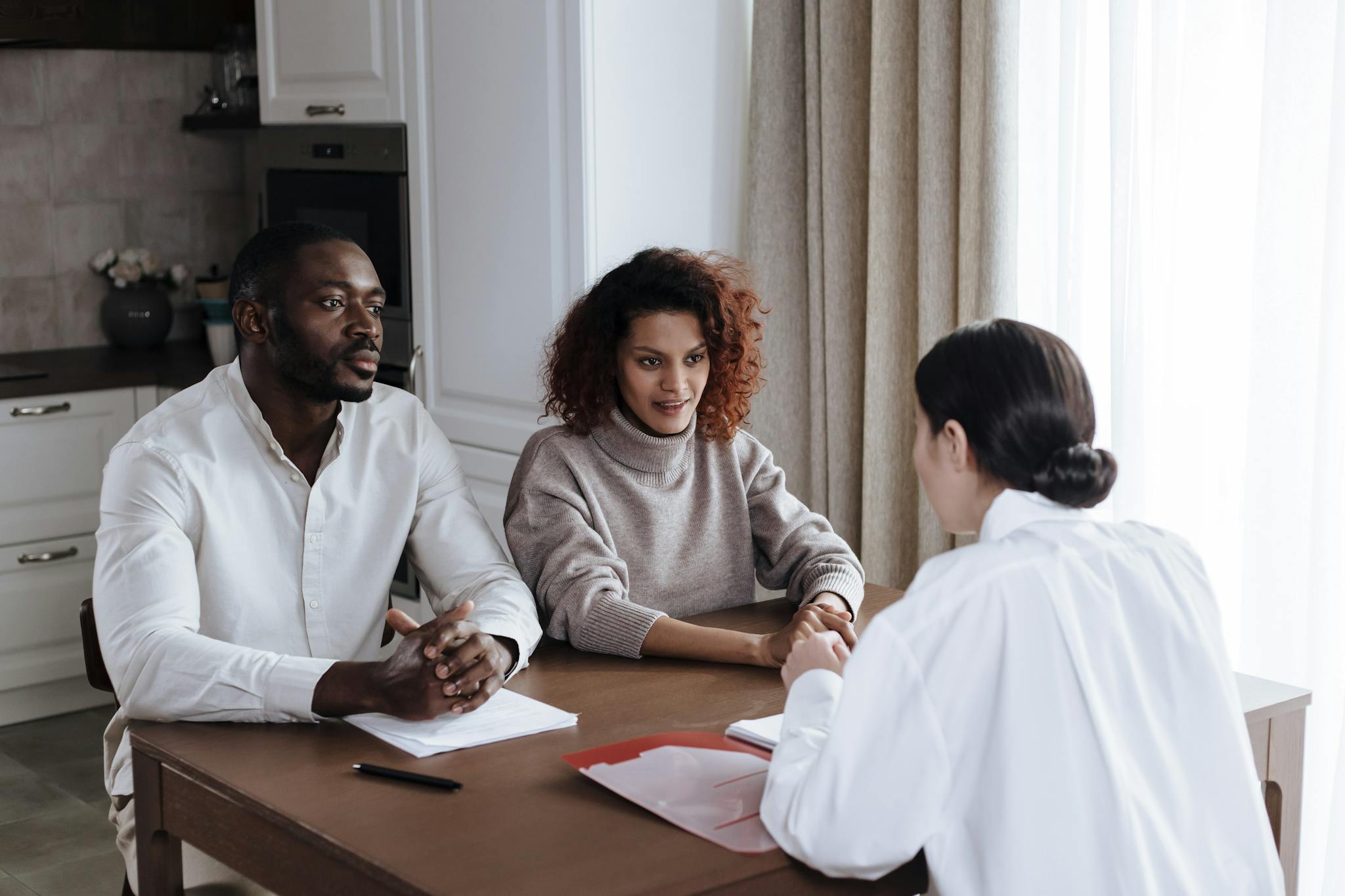 Man and woman discussing documents with a social worker at home.